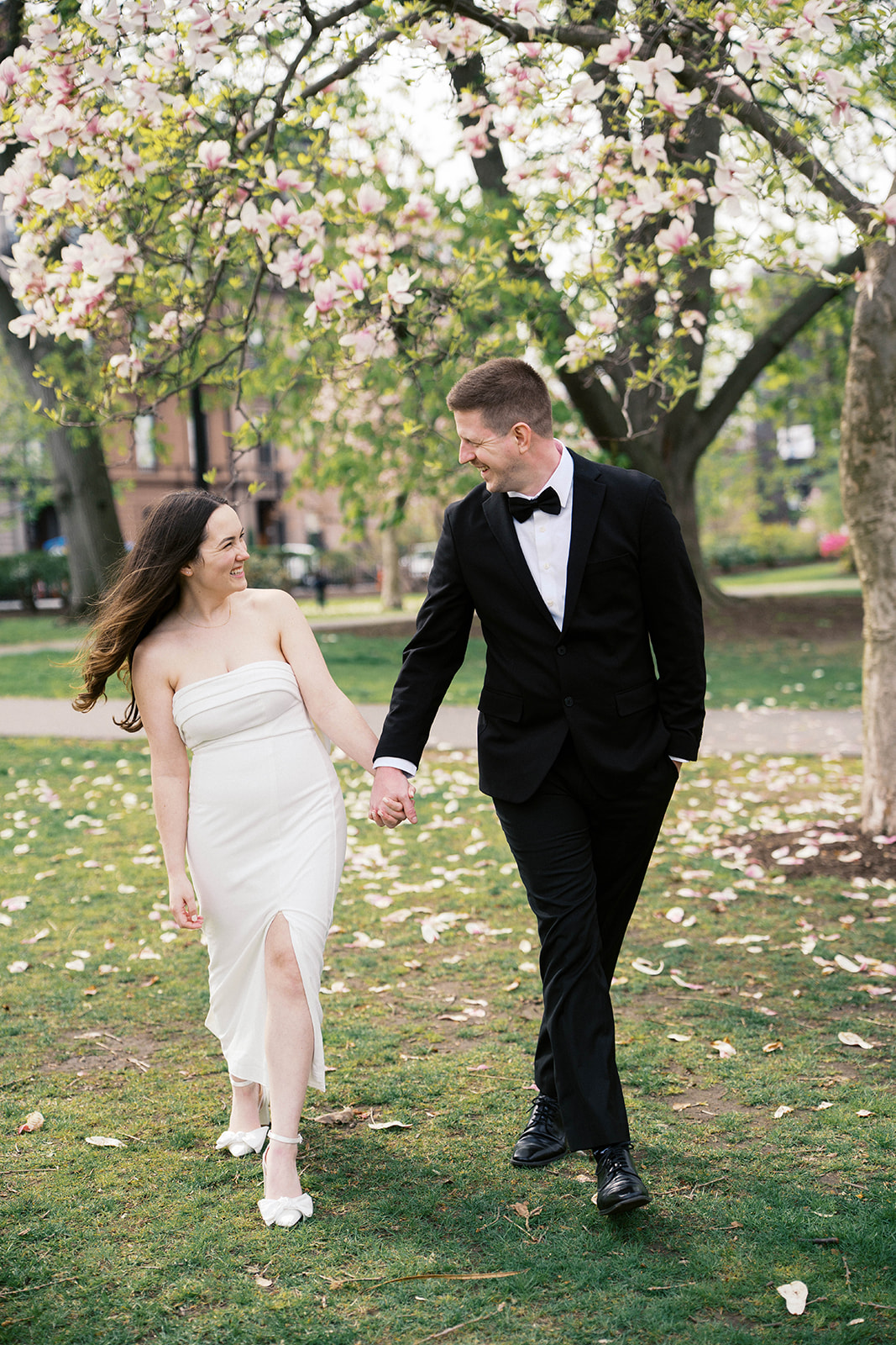 elopement couple walks under magnolia tree in Boston Public Gardens
